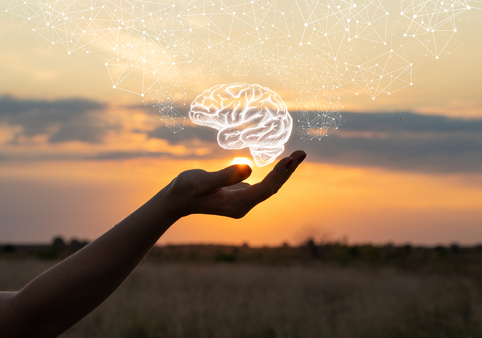 GettyImages-1031563502 A hand holding out a glowing brain in the air.