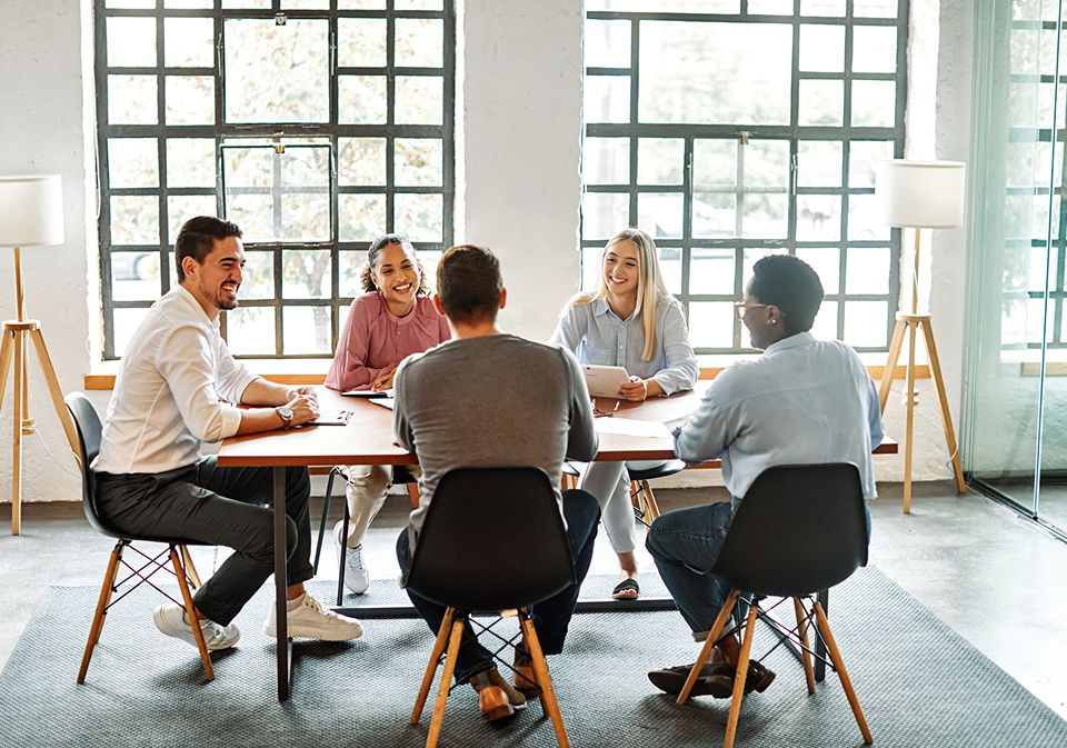 GettyImages-1444802135 A group of people sitting around a table.