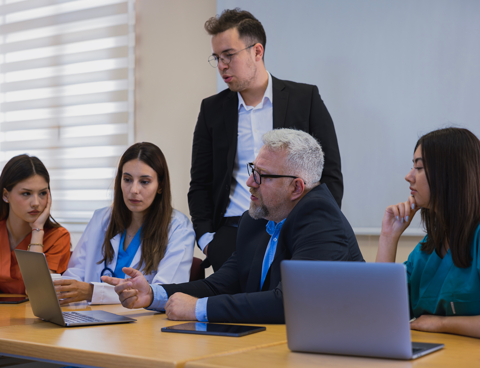 A group of people sitting at a table with laptops.