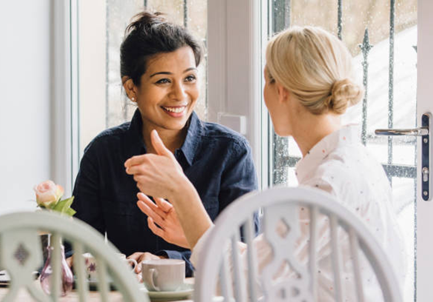 Two women chatting at a cafe table.